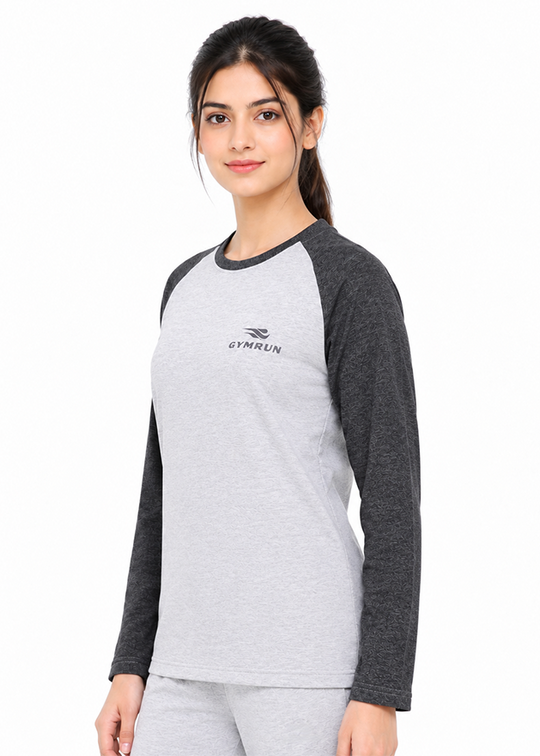 A woman modeling a long-sleeve raglan t-shirt in light gray and dark gray, featuring a small black 'GYMRUN' logo on the left chest, set against a plain white background.