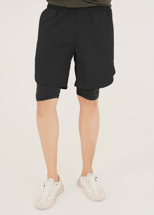 Person wearing black shorts on a plain background