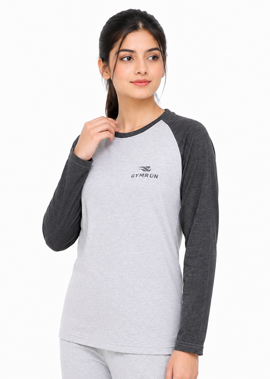 A woman modeling a heather gray and dark gray raglan long-sleeve top with a small dark gray 'GYMRUN' logo on the chest, set against a plain white background.
