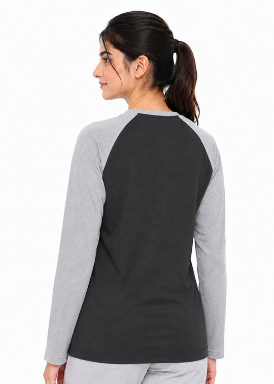 A woman shown from the back wearing a long-sleeve raglan shirt with a dark charcoal body and light gray sleeves, paired with light gray sweatpants, against a plain white background.