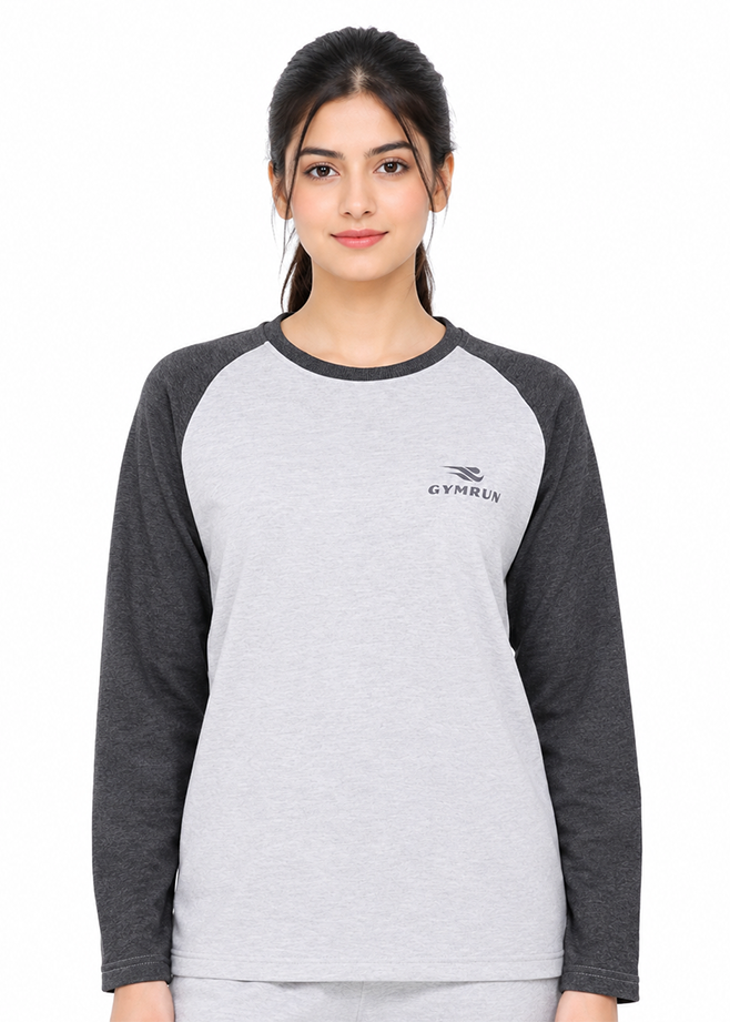 A woman modeling a light gray and dark gray raglan long-sleeve t-shirt with a small black GYMRUN logo on the left chest, shot against a plain white background.