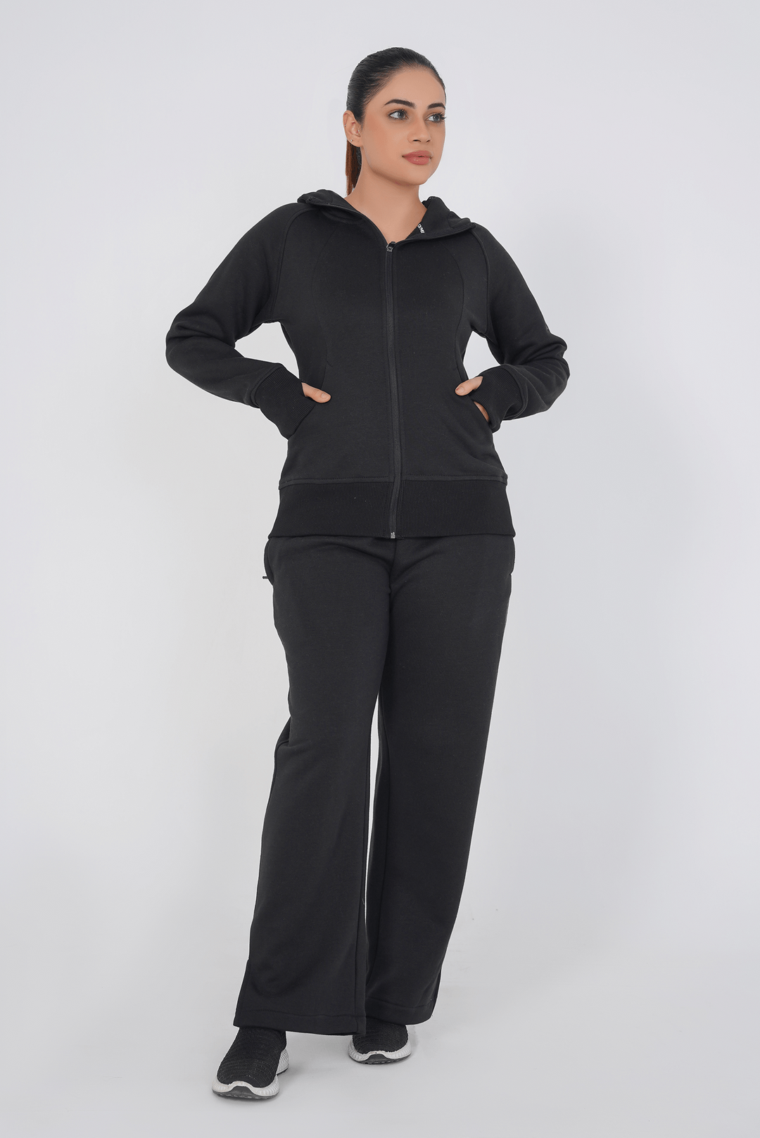 Woman wearing a black hoodie and pants on a white background