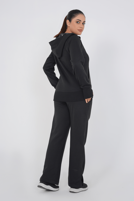 Woman wearing a black hoodie and pants on a white background