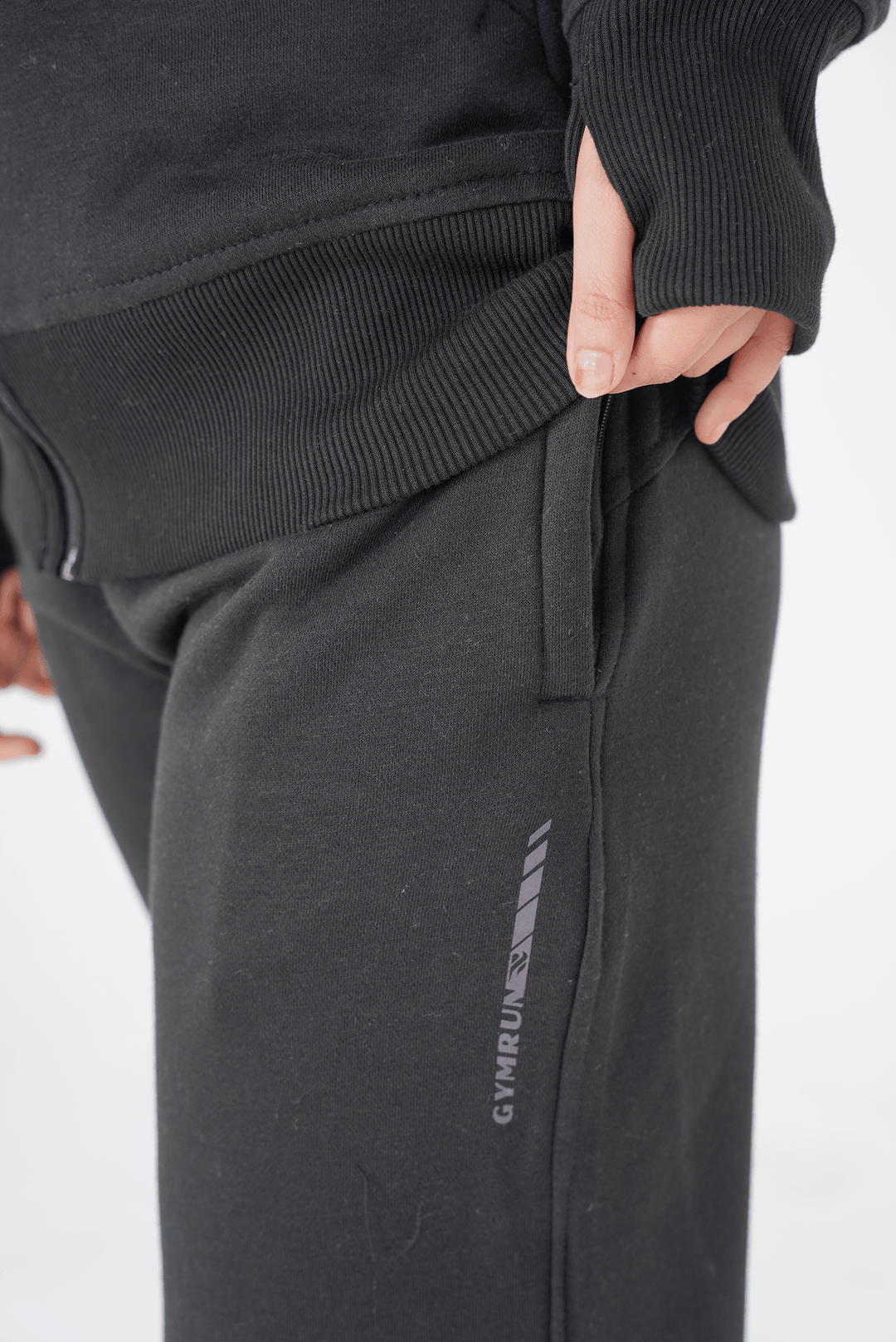 Person wearing black jogger pants with a brand logo on a white background