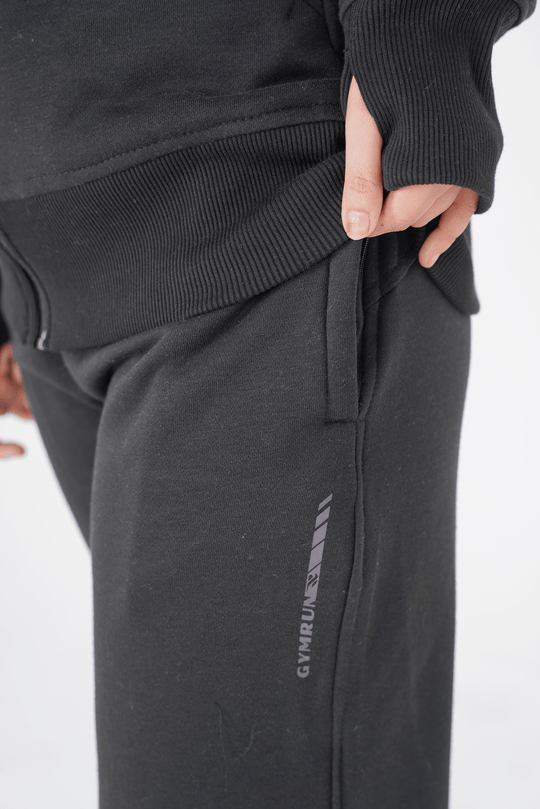 Person wearing black jogger pants with a brand logo on a white background