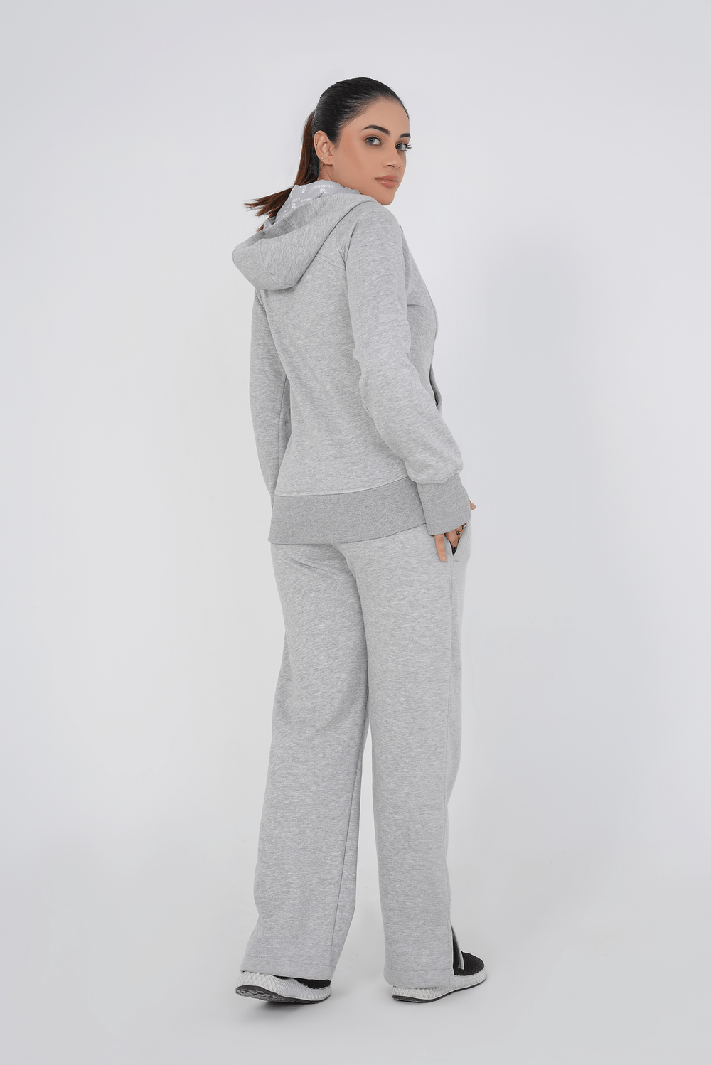 Person wearing a gray tracksuit on a white background