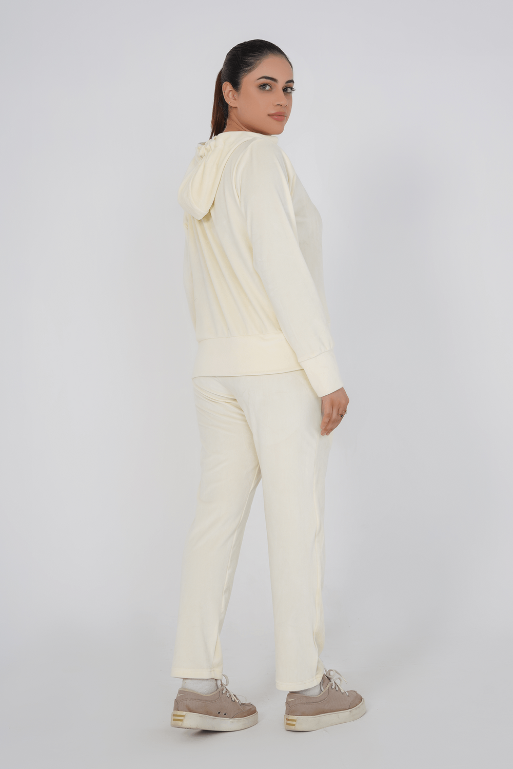 Person wearing a cream-colored hoodie and pants on a white background