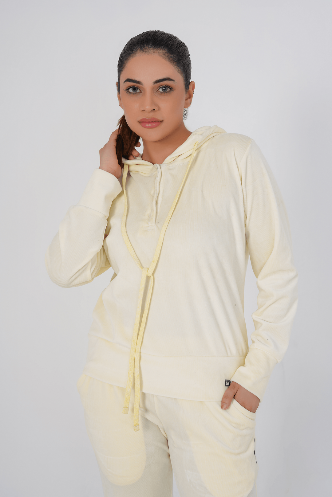 Woman wearing a cream-colored onesie with a hood against a white background