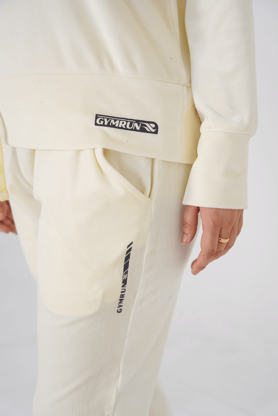 Person wearing a cream tracksuit with 'GYMRUN' branding on a white background