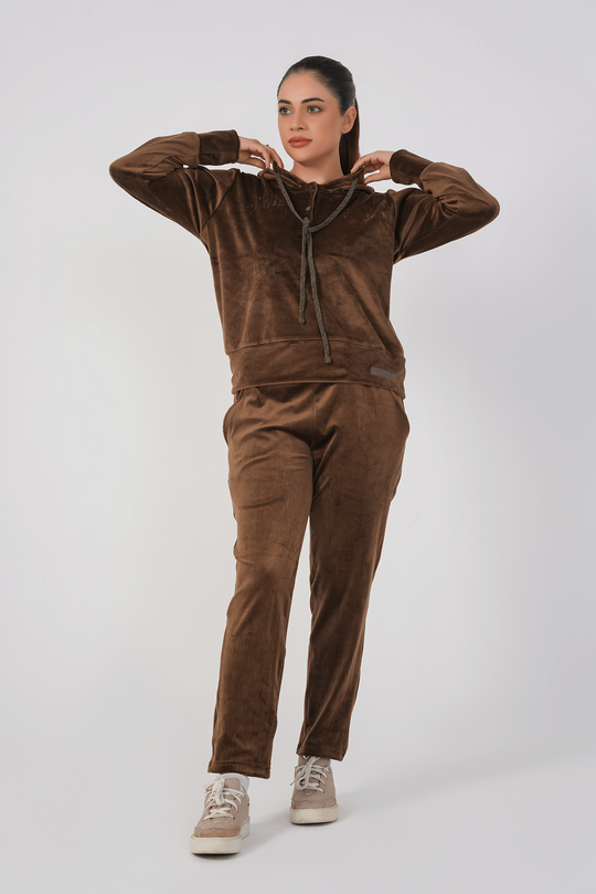 Person wearing a brown velour tracksuit on a white background