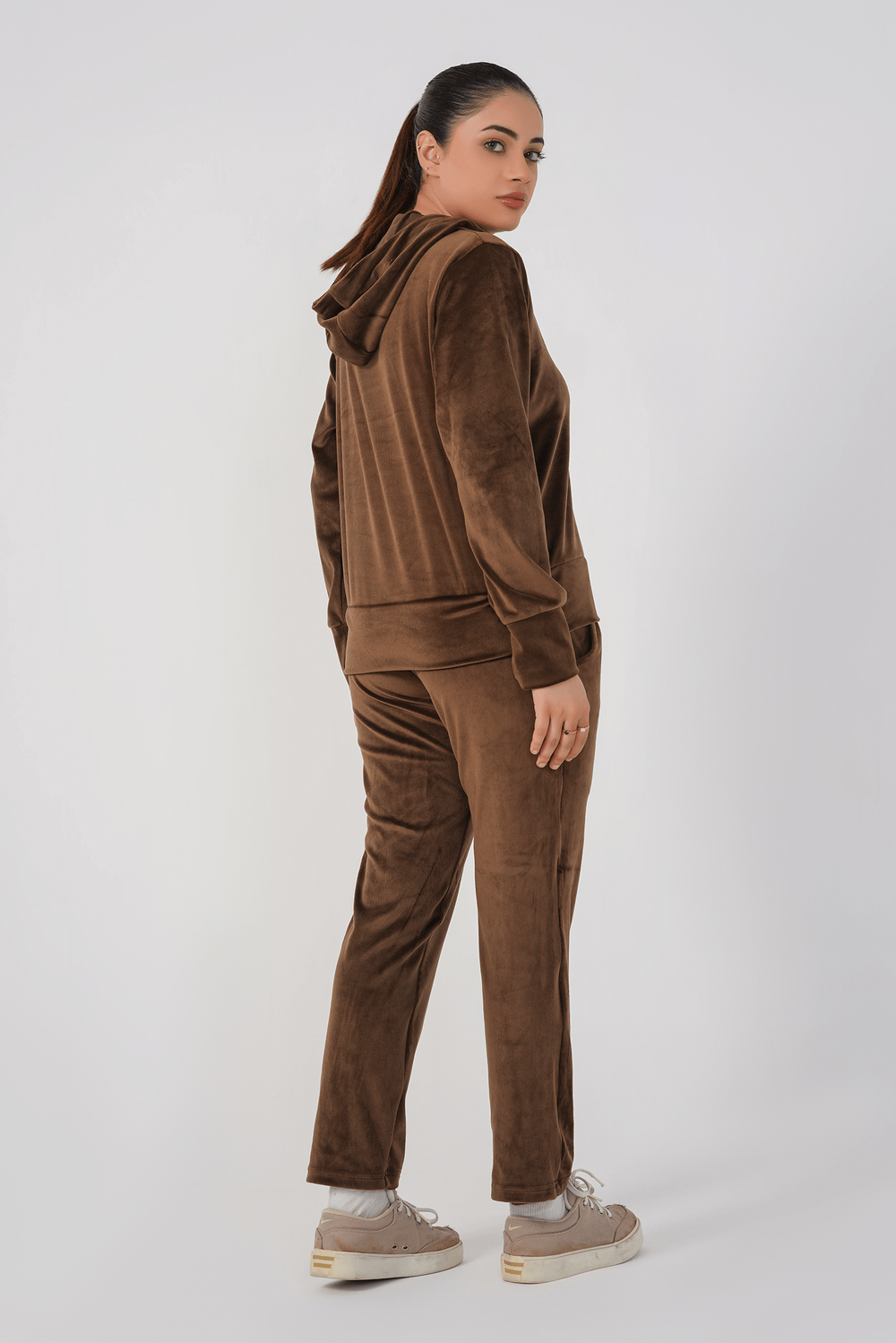Person wearing a brown corduroy tracksuit on a white background