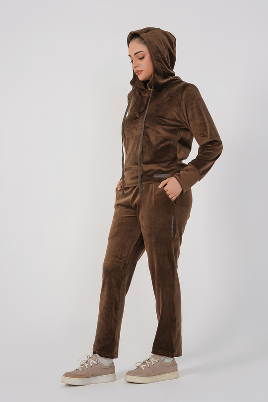 Person wearing a brown velour tracksuit on a white background