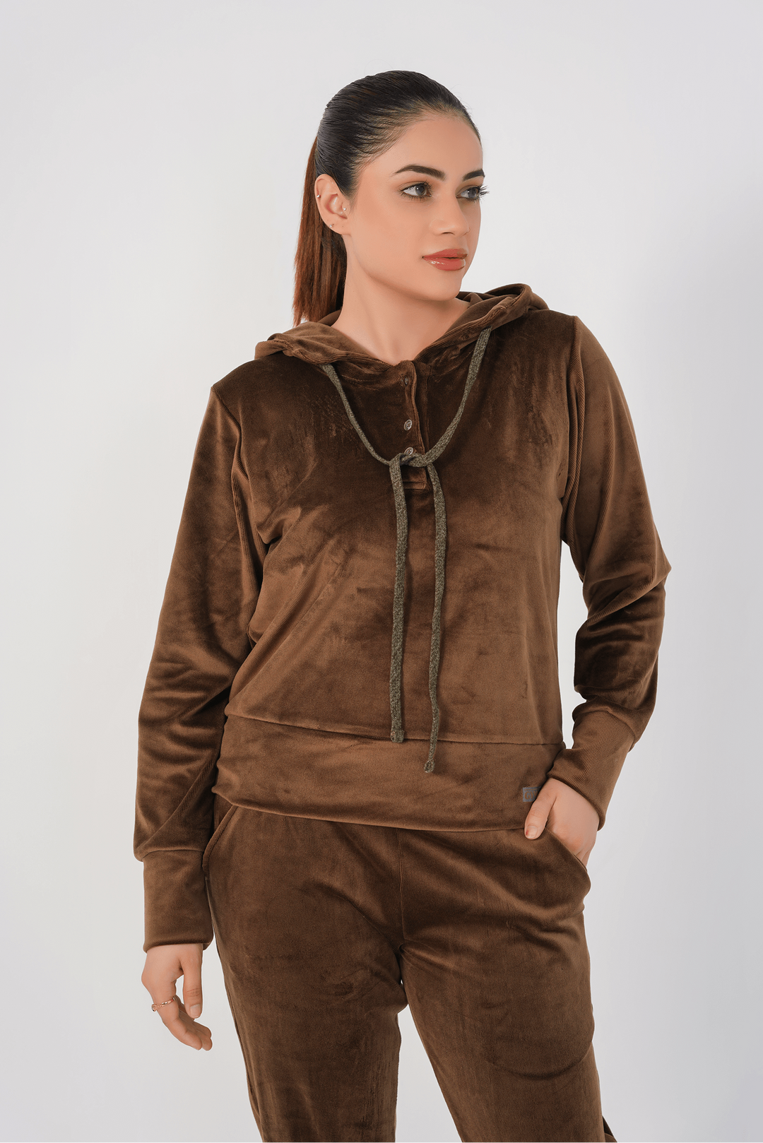 Woman wearing a brown velour tracksuit against a white background