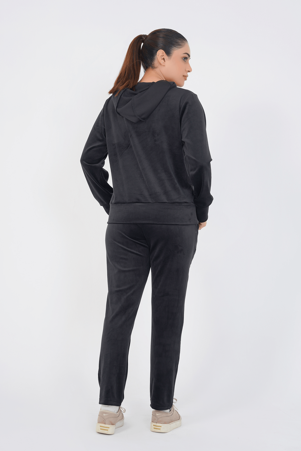 Person wearing a black hoodie and pants set on a white background