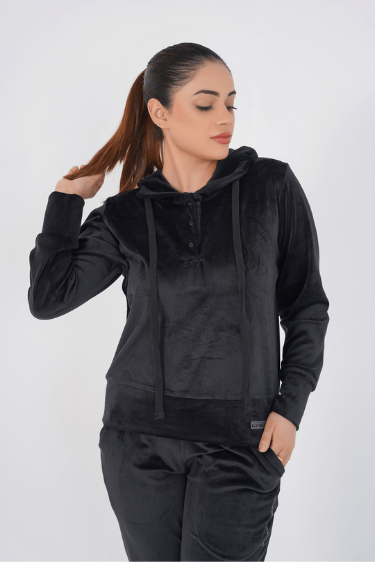 Woman wearing a black hoodie and pants against a white background