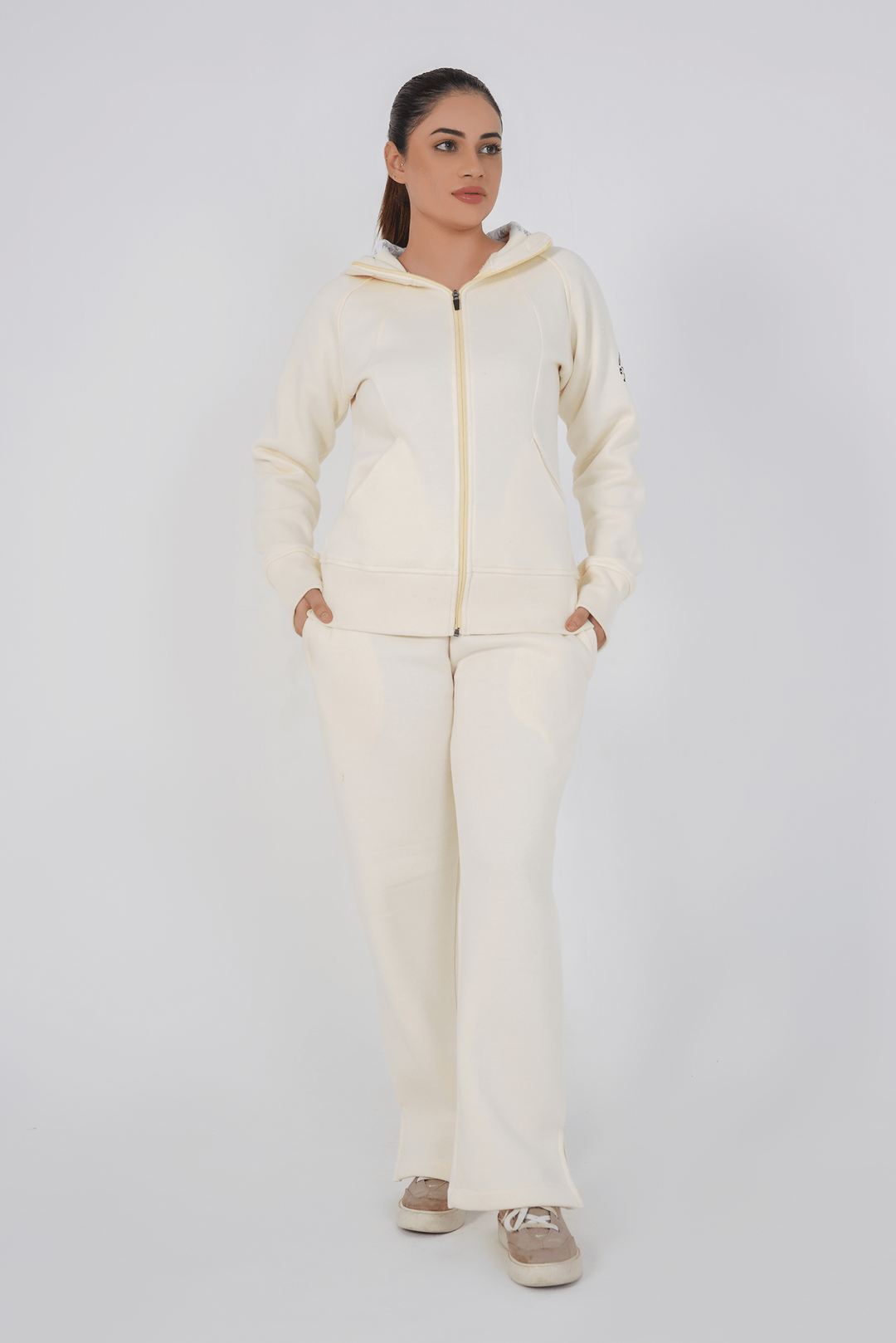 Woman wearing a cream-colored hoodie and pants on a white background