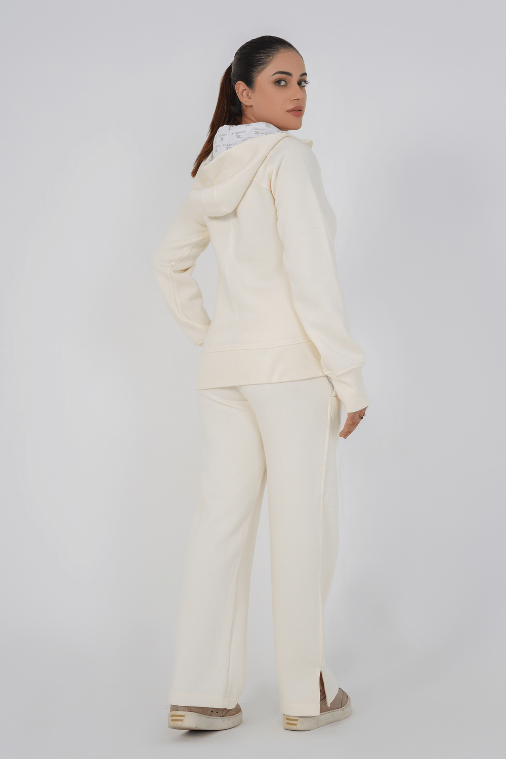 Woman wearing a cream-colored outfit with a matching jacket and pants on a white background