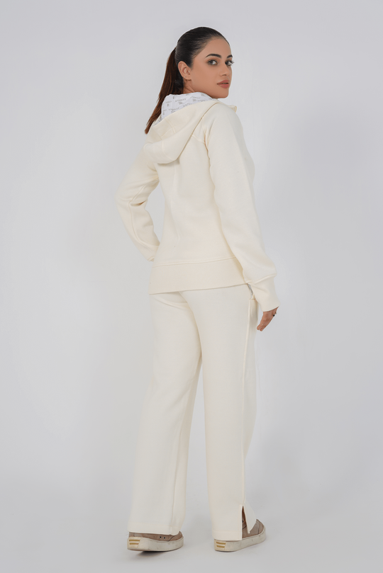 Woman wearing a cream-colored outfit with a matching jacket and pants on a white background
