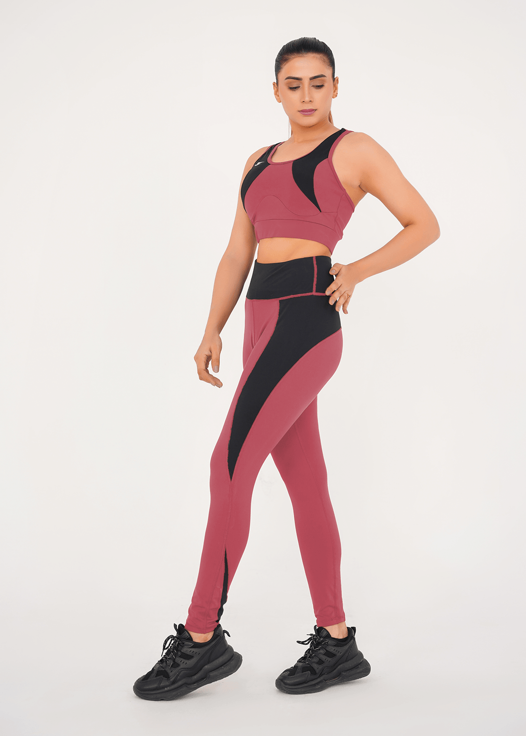 Woman wearing a maroon and black athletic outfit on a white background