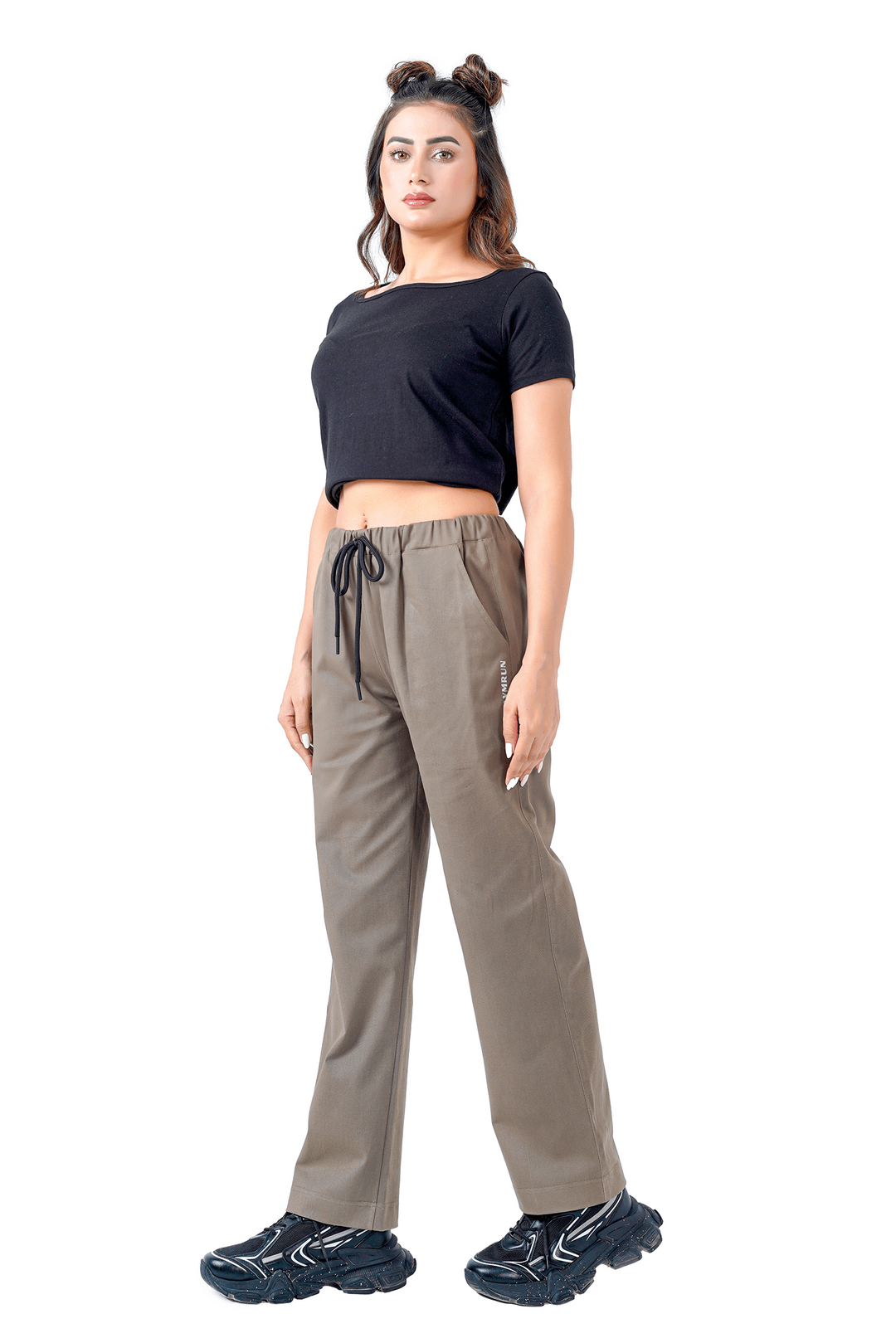 Woman wearing a black crop top and beige pants on a white background