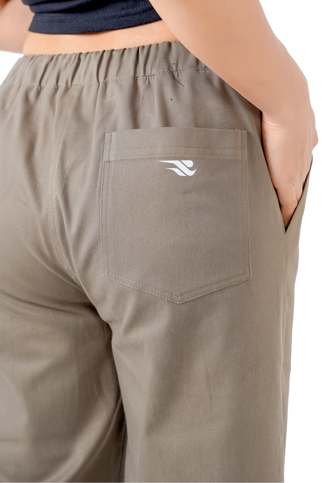 Person wearing beige pants with a logo on the pocket against a white background